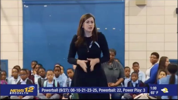 Woman speaks in front of a group of children on News 12 Brooklyn