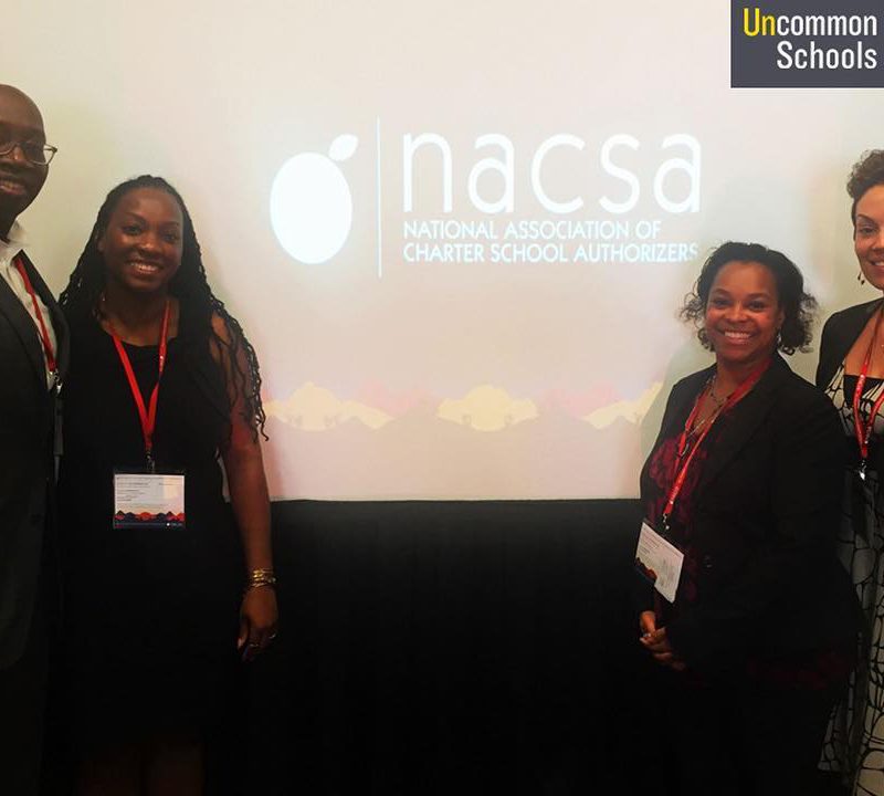 A man and three women pose in front of National Association of Charter School Authorizers presentation