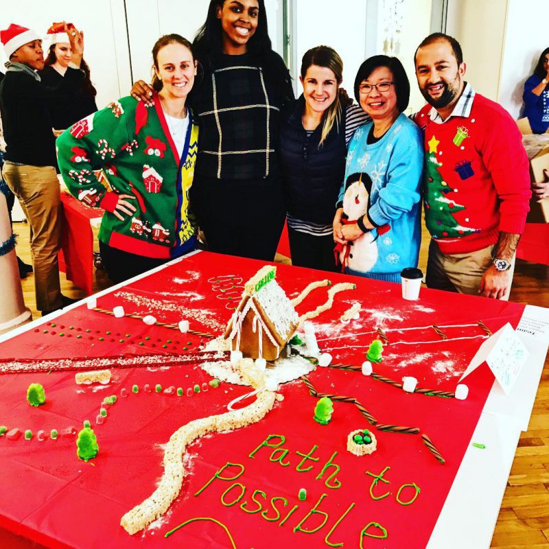Group poses behind gingerbread house