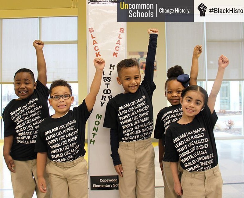 Students raise fists in the air wearing Black History Month shirts