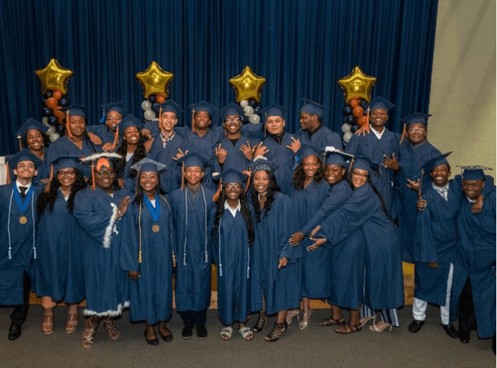 Group of students pose with smiles wearing their graduation caps and gowns