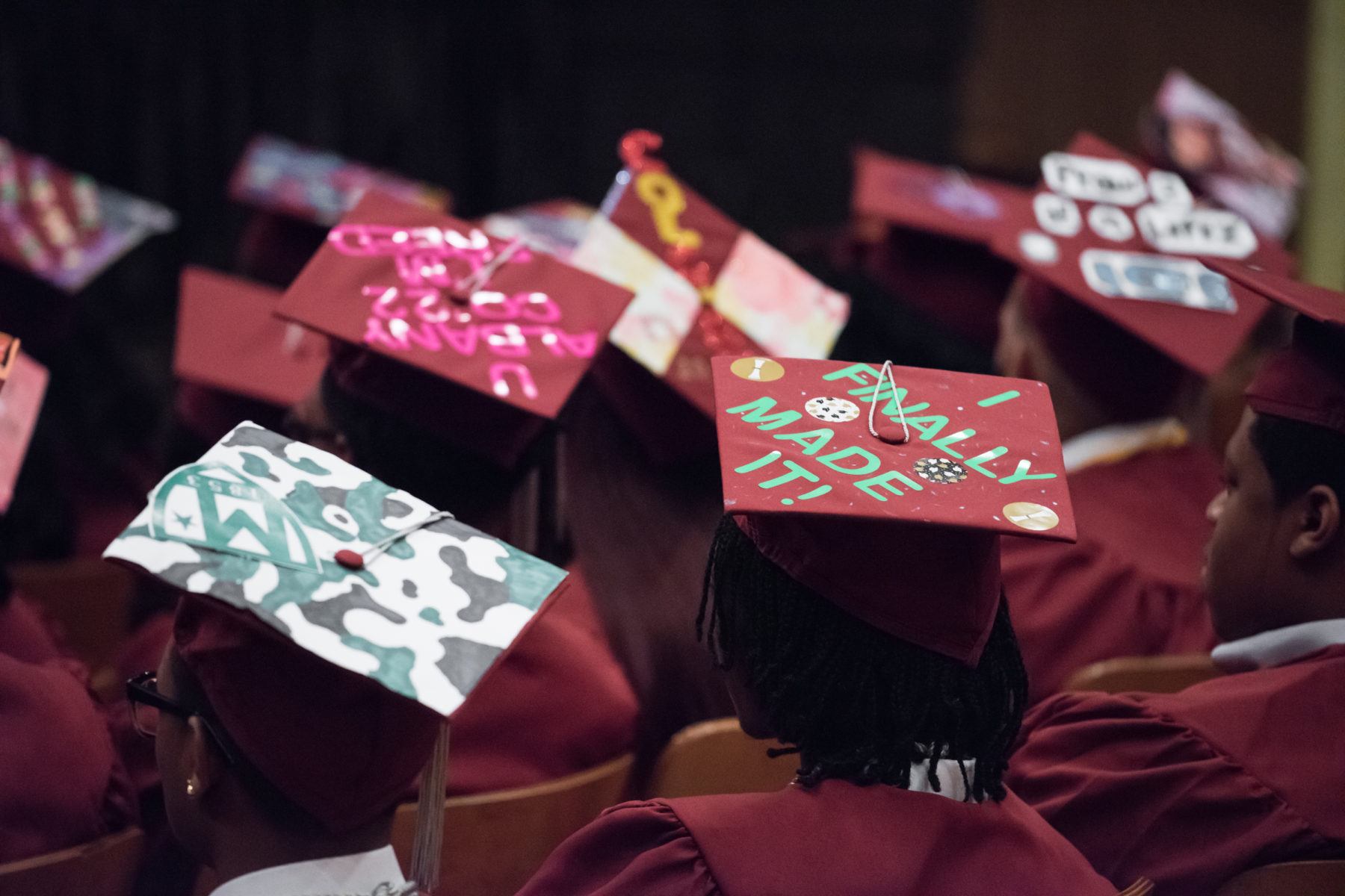 Students wearing graduation caps with one decorated to say "I finally made it!"