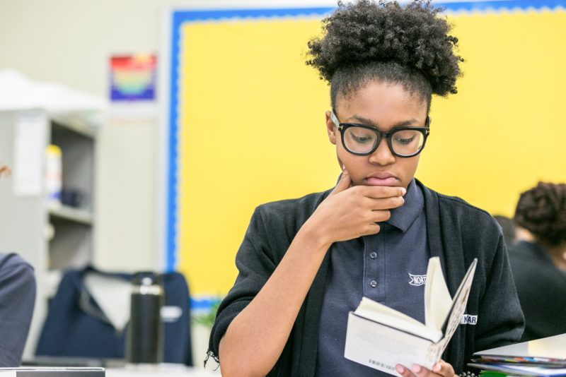 Student contemplating while reading a book