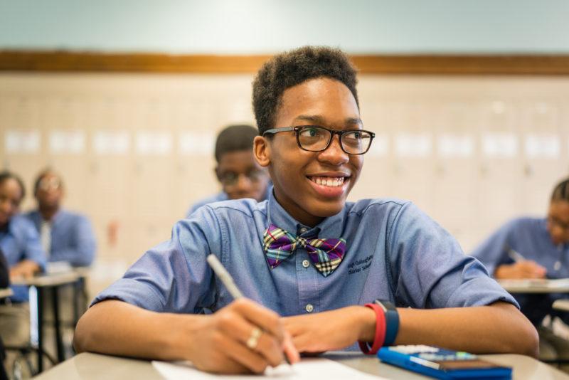 Student smiling with pen in hand