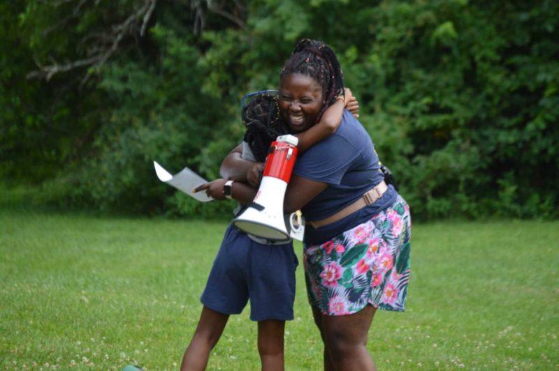 Woman with megaphone hugging student