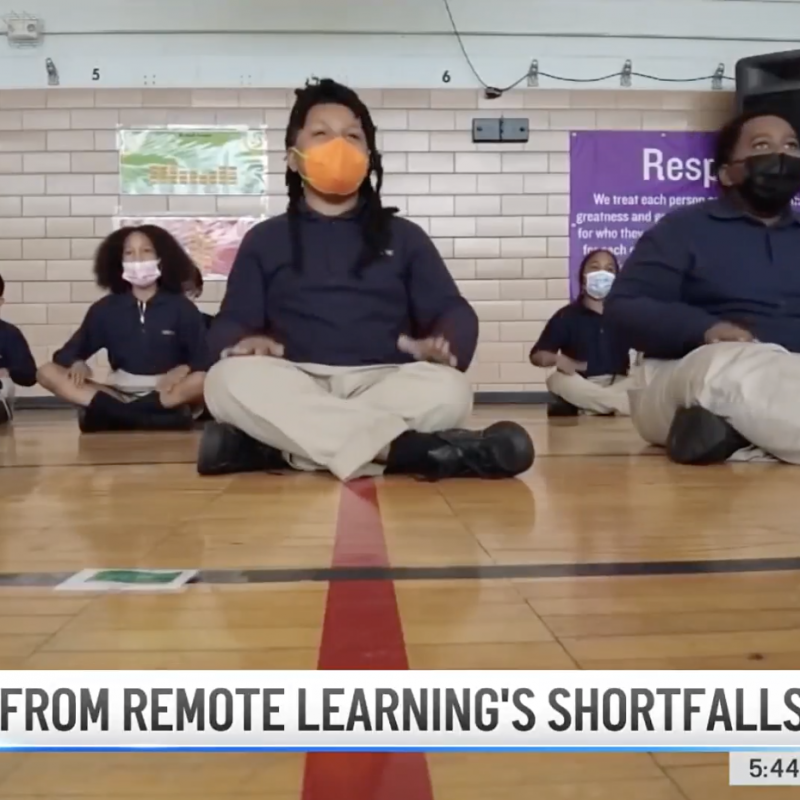 Screenshot from news report on how North Star academy is recovering from remote learning's shortfalls. Pictures images of students sitting on floor during pep rally