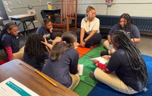 students and teacher sat together in a circle