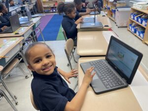 female student smiling while working on a laptop